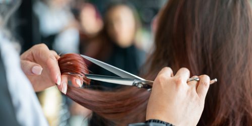 Close up of unrecognizable hairdresser cutting a female customerâs hair - Small business concepts